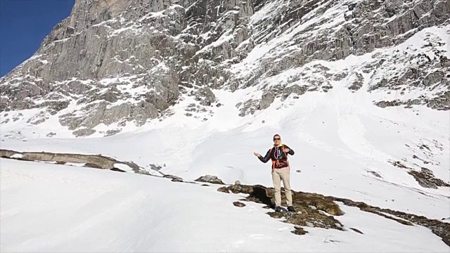 一名男性徒步旅行者将雪球扔向照相机，山脉视频素材