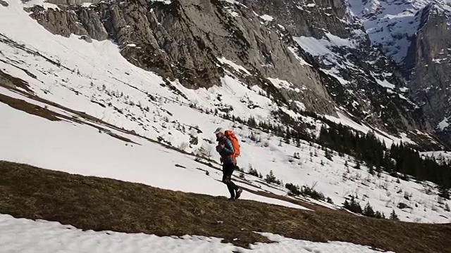 一位女性徒步者走在雪山下，停下来欣赏风景视频素材