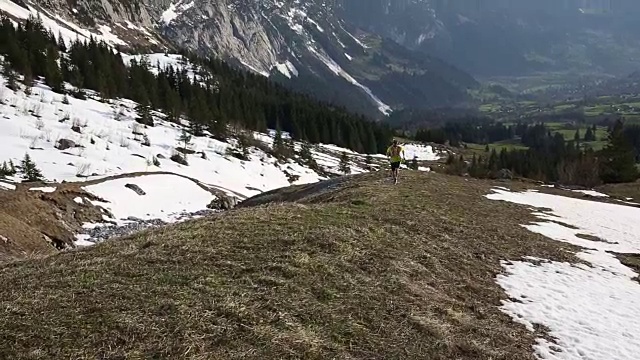 跑步者攀登陡峭的山坡，上面覆盖着积雪的山峰视频素材