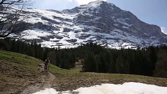 山地车沿着雪山下的小径下山视频素材