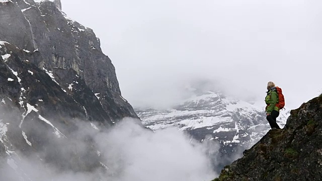 一名女性徒步者在攀登雪山下的山脊时停下来视频素材