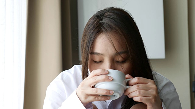 亚洲年轻女子在家里喝咖啡早上视频素材