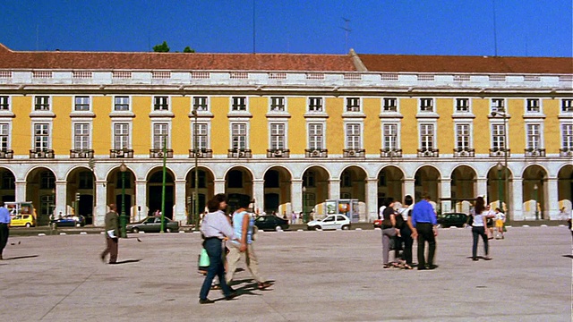 葡萄牙里斯本，人们在Praca do Comercio /背景中的黄色建筑中行走视频素材