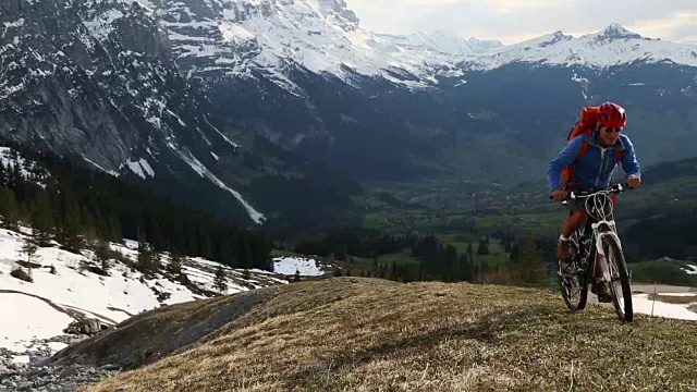 山地车在雪山下爬坡，停下来欣赏风景视频素材