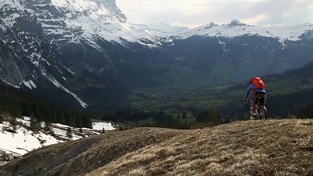 骑山地车的人从雪山下的斜坡下来，停下来欣赏风景视频素材