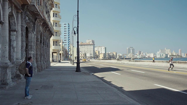 哈瓦那古巴马列孔路建立拍摄。街道上有经典的美国老爷车，人们在墙上行走或停留。视频素材