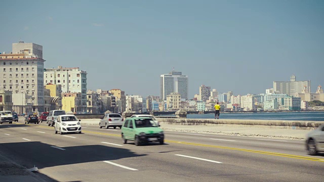 哈瓦那古巴马列孔路建立拍摄。街道上有经典的美国老爷车，人们在墙上行走或停留。视频素材