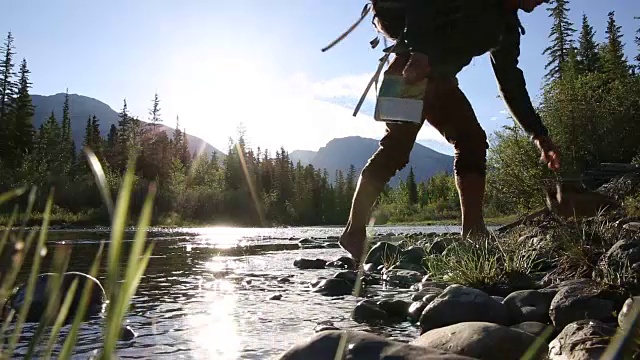 徒步旅行者沿着山涧跋涉，然后在岸上休息视频素材