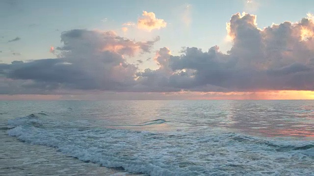 太阳升起时，温和的波浪滚上岸来视频素材