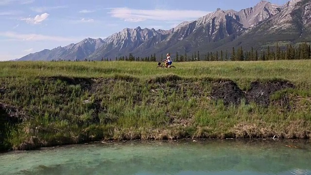 女人骑着自行车在广阔的山区景观，上面的湖视频素材