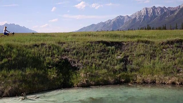 女人骑着自行车在广阔的山区景观，上面的湖视频素材