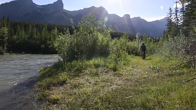 骑山地车的人骑着自行车进入河流浅滩，穿过森林视频素材