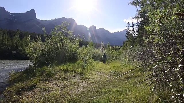 骑山地车的人骑着自行车进入河流浅滩，穿过森林视频素材