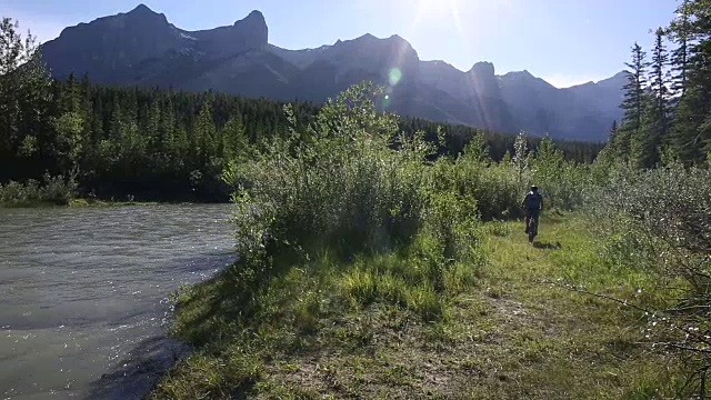 骑山地车的人骑着自行车进入河流浅滩，穿过森林视频素材