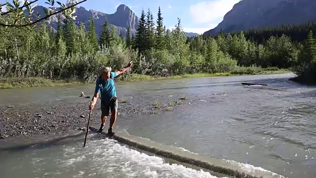 一名男性徒步旅行者用淹没在水中的原木涉水过山溪视频素材