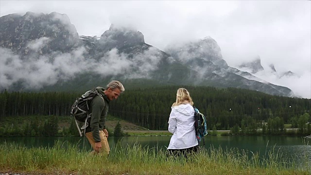 徒步旅行的夫妇在山湖边停下来，打水漂视频素材