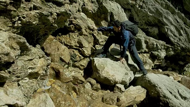 在崎岖地带攀登岩石的登山者。视频素材