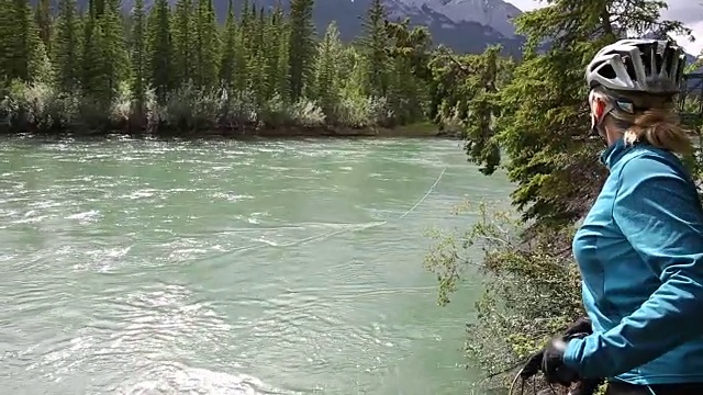 女山地自行车手到达河边，森林下面，山脉视频素材