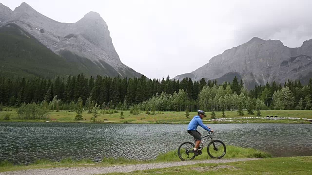 一名男性山地自行车手沿着山湖边的小路行驶视频素材