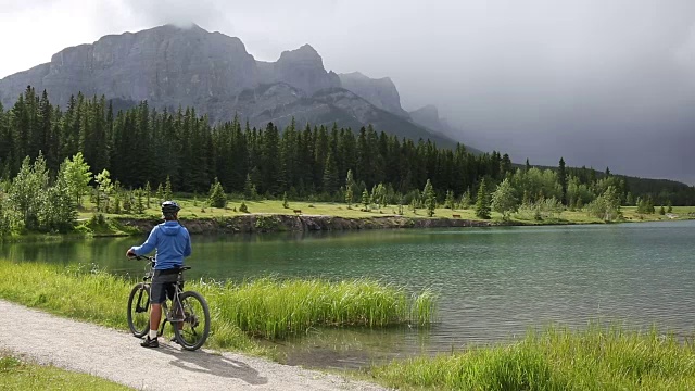 一名男性山地自行车手沿着山湖边的小路行驶视频素材