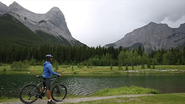 一名男性山地自行车手沿着山湖边的小路行驶视频素材