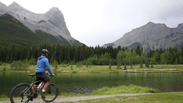 一名男性山地自行车手沿着山湖边的小路行驶视频素材