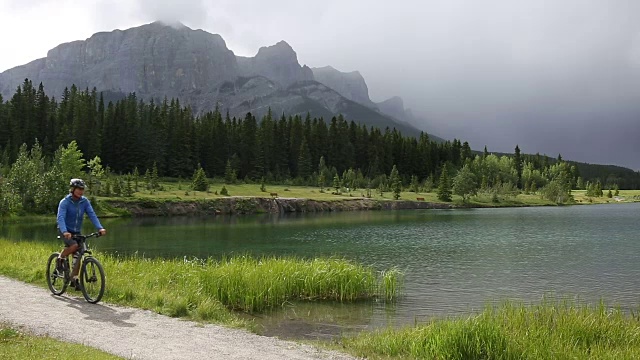 一名男性山地自行车手沿着山湖边的小路行驶视频素材