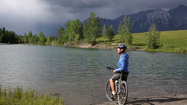 一名男性山地自行车手沿着山湖边的小路行驶视频素材