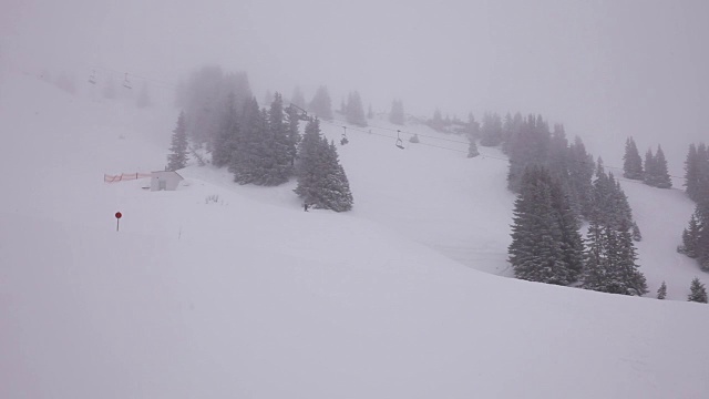 有雾，山上的雪景上正在下雪。人们在底部滑雪和滑雪缆车。视频素材