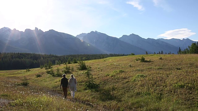 成熟的情侣走过高山草地，日出视频素材