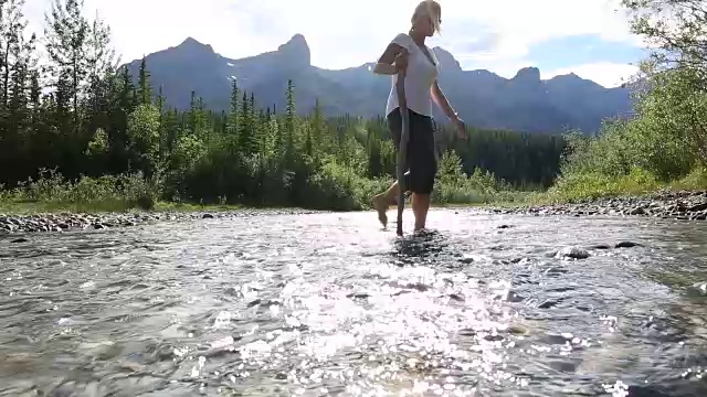 一对夫妇涉水穿过山间小溪，从卵石滩到对岸视频素材