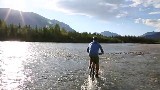 骑山地车的男子渡河向远山走去视频素材