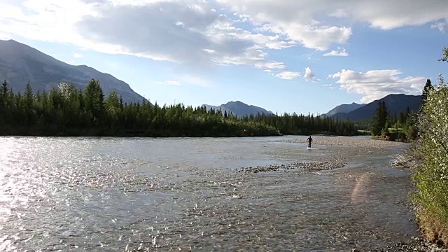 男性山地自行车骑手穿过河流远离遥远的山脉视频素材