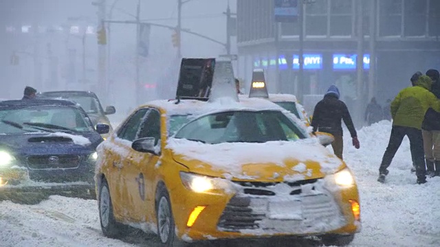 摄像头捕捉到了乔纳斯冬季暴风雪期间第六大道的交通状况。道路和汽车被雪覆盖，能见度不利于下雪。人们帮助从厚厚的积雪中逃出堆叠的出租车。视频素材