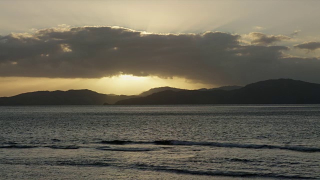 日落时海浪在平静的海面上，太阳在云后面视频素材