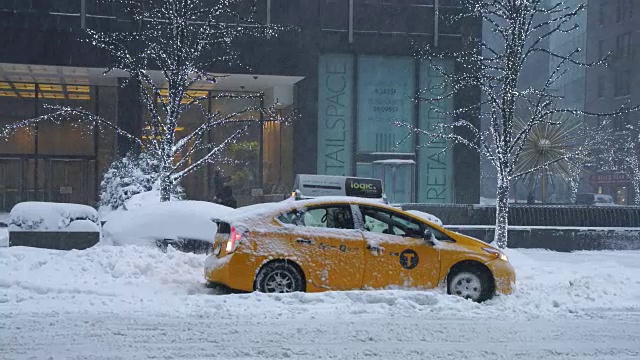 摄像头捕捉到了乔纳斯冬季暴风雪期间第六大道的交通状况。道路和汽车被雪覆盖，能见度不利于下雪。出租车的轮胎在深深的雪地里打滑，汽车被卡住了。视频素材