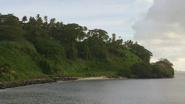 平静的海浪冲刷着岩石嶙峋的海岸线，那里长满了繁茂的树木和树叶视频素材