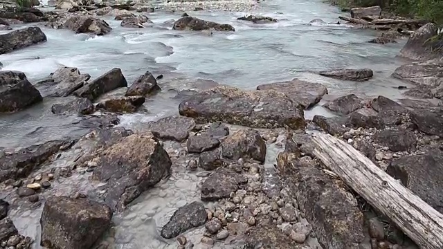 一名男性徒步者走到河边，眺望着暴风雨般的山脉视频素材