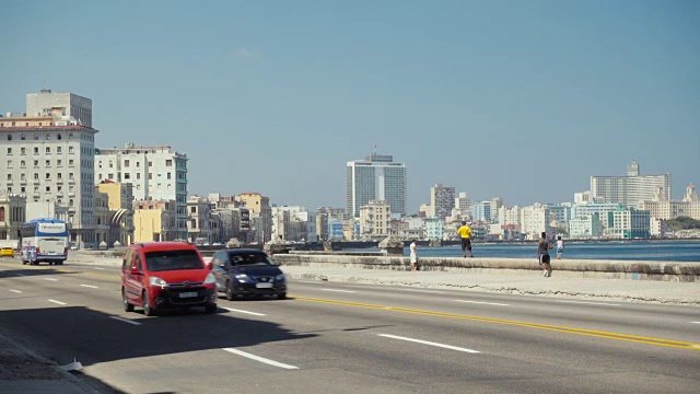 哈瓦那古巴马列孔路建立拍摄。街道上有经典的美国老爷车，人们在墙上行走或停留。视频素材