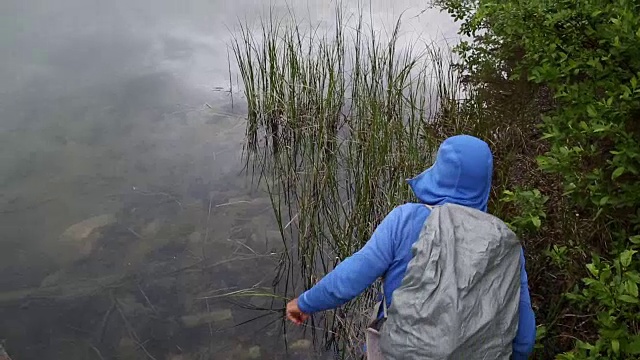 一名男性徒步者在暴雨中探索山湖岸线视频素材