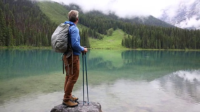 一名男性徒步者在暴风雨后探索山湖岸线视频素材