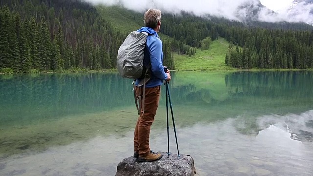 一名男性徒步者在暴风雨后探索山湖岸线视频素材