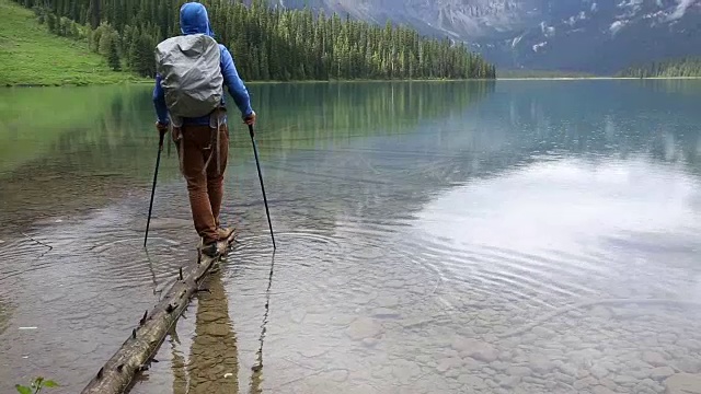 一名男性徒步者在暴雨中探索山湖岸线视频素材