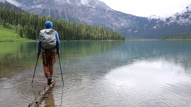 一名男性徒步者在暴雨中探索山湖岸线视频素材