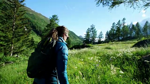 日落时分，一名女性徒步旅行者穿过高山草地视频素材