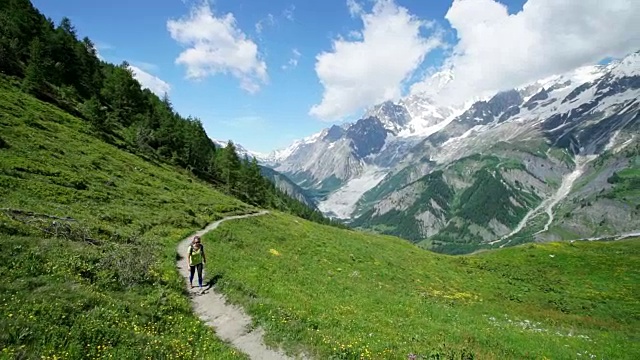 女性徒步旅行者沿着雪山下的山道行走视频素材