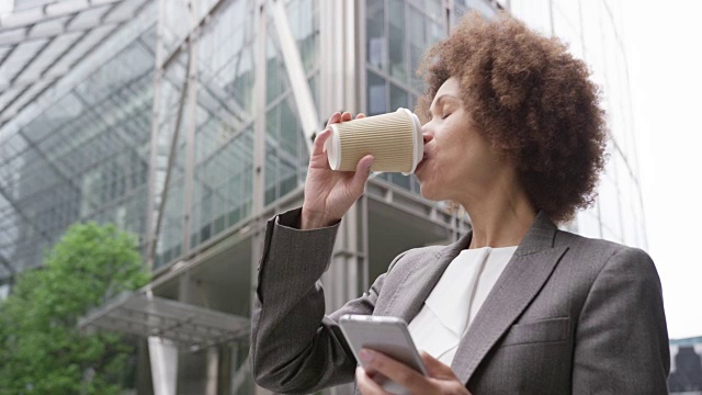 非裔美国女商人在城市里用智能手机买外卖咖啡视频素材