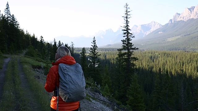 清晨，一名女性徒步旅行者沿着山路行走视频素材