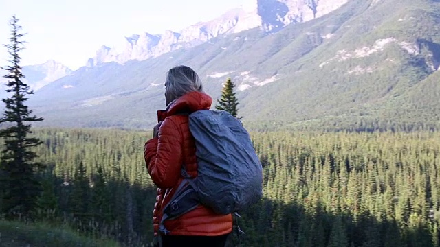 清晨，一名女性徒步旅行者沿着山路行走视频素材