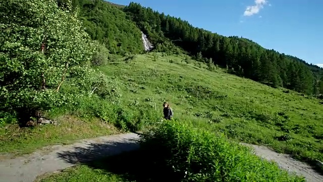 女性徒步旅行者走在雪山下的道路上视频素材